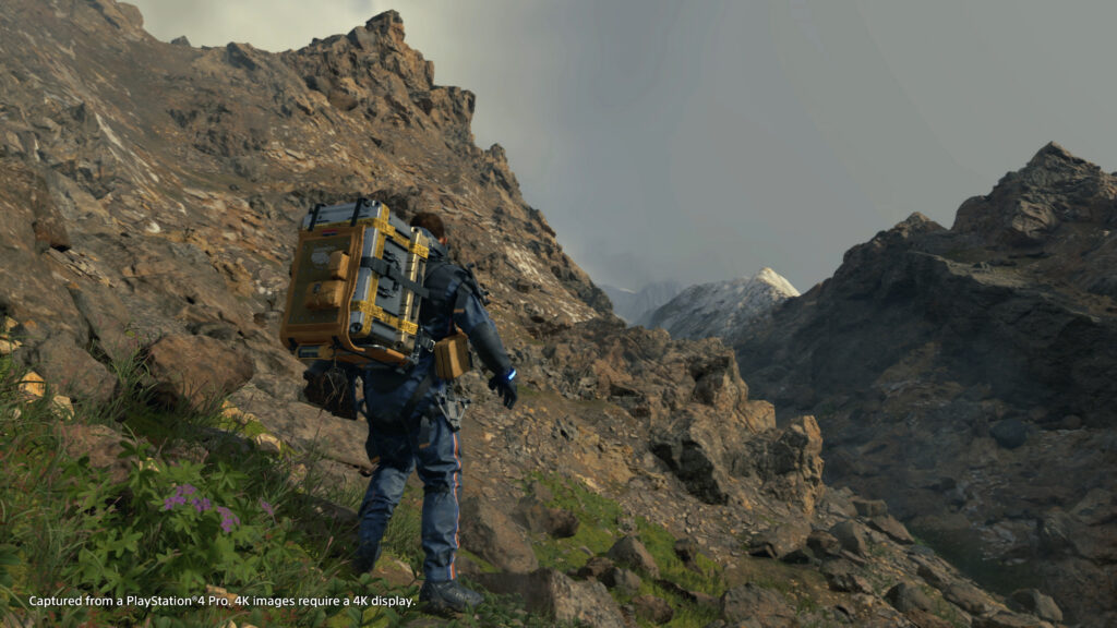 Sam traversing a mountain in Death Stranding, which is sure to look better in the Director's Cut. 